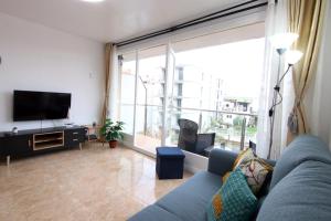 a living room with a blue couch and a large window at Apartment with balcony close to the beach in Lloret de Mar