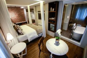 a small room with a bed and a table and a bathroom at Hotel Cercano in Gramado