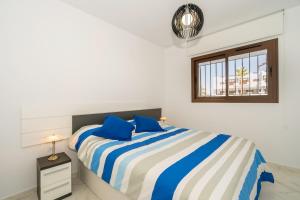 um quarto com uma cama com almofadas azuis e uma janela em Nardos em San Juan de los Terreros