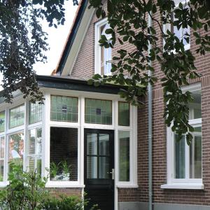 een huis met witte ramen en een zwarte deur bij Appartement 'Wij en de Zande' in Kamperveen