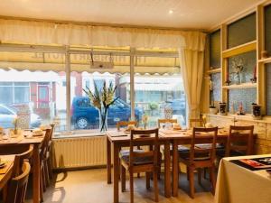 a dining room with tables and chairs and a window at Highbury Hotel in Blackpool