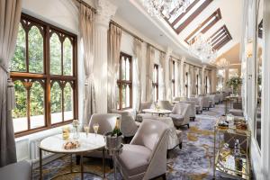 a restaurant with tables and chairs and windows at Tullyglass House Hotel in Ballymena
