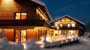 a house covered in snow in front of a house at freistil Boutiquehotel in Sonthofen