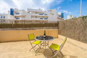 a table and chairs on a patio with a bottle of wine at El Bosque in Orihuela Costa