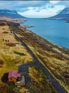 an aerial view of a house on a hill next to the water at Langahlid Cottages & Hot Tubs in Seyðisfjörður