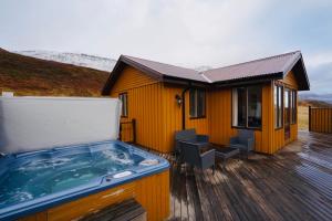 uma banheira de hidromassagem num deque ao lado de uma casa em Langahlid Cottages & Hot Tubs em Seyðisfjörður