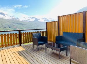 a deck with two chairs and a table with a view at Langahlid Cottages & Hot Tubs in Seyðisfjörður