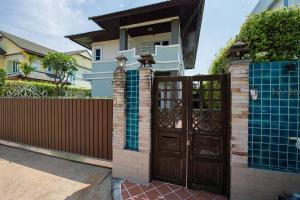 una casa con una puerta de madera y una valla en Private Pool Villa Beach WashMachine @Rayong會說中文 en Ban Nong Si Tong