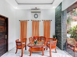 uma sala de jantar com mesa e cadeiras e um relógio em SUPER OYO 90672 ADHYA GUEST HOUSE LOMBOK em Tjakranegara