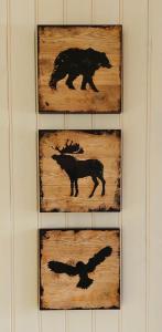 four pieces of wood with silhouettes of animals on a wall at Langahlid Cottages & Hot Tubs in Seyðisfjörður