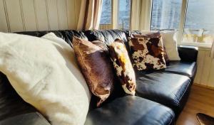 a black leather couch with pillows on it at Langahlid Cottages & Hot Tubs in Seyðisfjörður