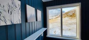 a room with a window and a snowy mountain at Langahlid Cottages & Hot Tubs in Seyðisfjörður