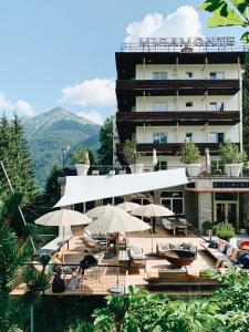 um hotel com cadeiras e guarda-sóis em frente a um edifício em Design Hotel Miramonte em Bad Gastein