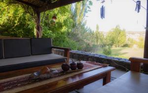 um alpendre com um banco, uma mesa e uma janela em Finca del Rio - Casa de campo em Tunuyán