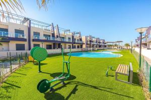 a playground in front of a building with a pool at Hierbas in Pilar de la Horadada