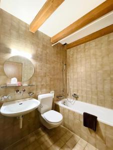 a bathroom with a toilet, sink and tub at Hotel du Cheval Blanc in Nods