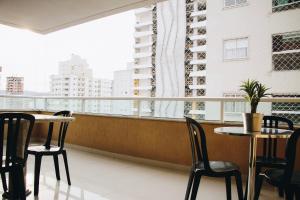 un balcón con mesas y sillas y una gran ventana en Apartamento em Itapema a 400m do mar, en Itapema