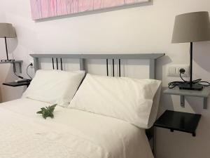 um quarto com uma cama branca e almofadas brancas em Apartamento entero a 10 minutos en coche de Sevilla Centro em Camas