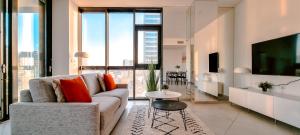 a living room with a couch and a tv at BnBIsrael apartments - HaYarkon Orchide in Tel Aviv
