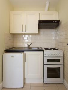 cocina con armarios blancos, fogones y nevera en Glencourt Apartments en Dublín