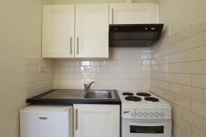 cocina con armarios blancos, fregadero y fogones en Glencourt Apartments en Dublín