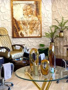 Masawara Urban Retreat في هراري: غرفة مع طاولة زجاجية عليها مزهريتين ذهبيتين