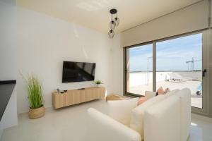 sala de estar con sofá blanco y TV de pantalla plana en Iris, en San Miguel de Salinas
