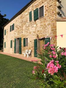 um edifício de tijolos com portas verdes, mesas e flores em Casa Brizzi em San Pietro