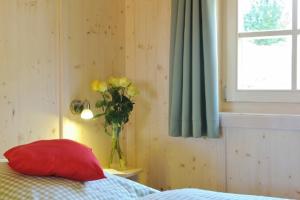 a bedroom with a red pillow and a vase of yellow flowers at Lamplhof in Rimsting