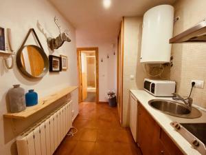 cocina con fregadero y microondas en Apartamentos Bluettravel Snow Confort Monte Gorbea, en Sierra Nevada