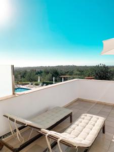 a balcony with a bench and a table and a pool at Casa Branca in Tavira