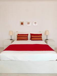 een witte slaapkamer met een groot wit bed met rode kussens bij Casa Branca in Tavira