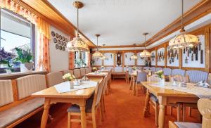 a restaurant with wooden tables and chairs and chandeliers at Haus Iris in Bodenmais