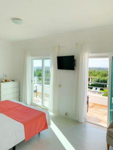 een witte slaapkamer met een bed en een glazen schuifdeur bij Casa Branca in Tavira
