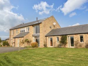 a large brick house with a lawn in front of it at Fontburn Farmhouse in Morpeth