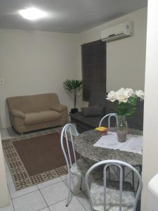 a living room with a table and chairs and a couch at Apto 2 quartos, cond fechado, com vaga, quarto andar in Pelotas