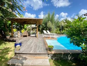 a backyard with a pool and a wooden deck with a pergola at Villa Aloha in Saint-François