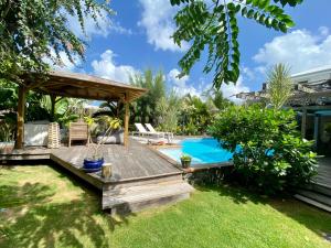 a backyard with a wooden deck and a swimming pool at Villa Aloha in Saint-François