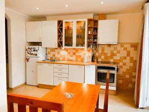 a kitchen with white cabinets and a wooden table at Terbatas Apartment in Rīga