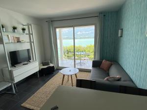 a living room with a couch and a large window at Vue sublime sur le lac du Bourget in Le Bourget-du-Lac
