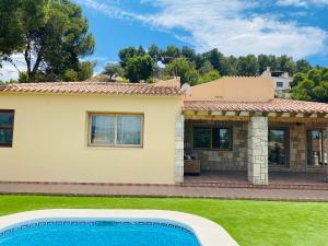 a villa with a swimming pool in front of a house at Family villa in Alicante, saltwater pool, AC and bbq in Alicante