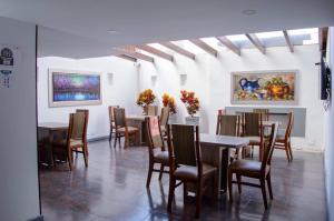 a dining room with tables and chairs and paintings at Hotel Confort 80 Zona Rosa in Bogotá