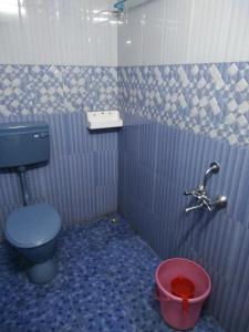 a bathroom with a blue toilet and a bucket at MANIIS HOMESTAY in Vālpārai