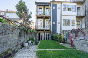 a house with a stone wall and a yard at Homely Noble Flats - Garden & Jacuzzi in Porto