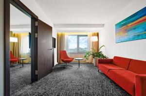 um quarto de hotel com um sofá vermelho e uma mesa e cadeiras em Park Inn by Radisson Kyiv Troyitska em Kiev