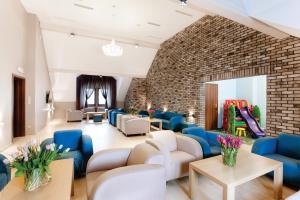 uma sala de espera com cadeiras azuis e brancas e uma parede de tijolos em Artus Resort em Karpacz