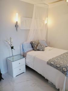 a bedroom with a white bed with a nightstand and a bed sidx sidx sidx at Emerald Garden in Ocho Rios