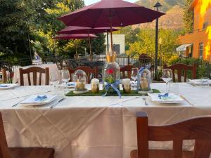 San Pietro InfineにあるHotel Ristorante Villa Pegasoの白いテーブルクロスと紫の傘が置かれたテーブル