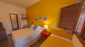 ein Schlafzimmer mit einem weißen Bett und einer gelben Wand in der Unterkunft Pousada Canto do Rio in Prado