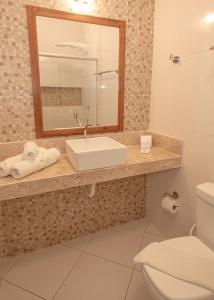 ein Badezimmer mit einem Waschbecken, einem Spiegel und einem WC in der Unterkunft Pousada Canto do Rio in Prado
